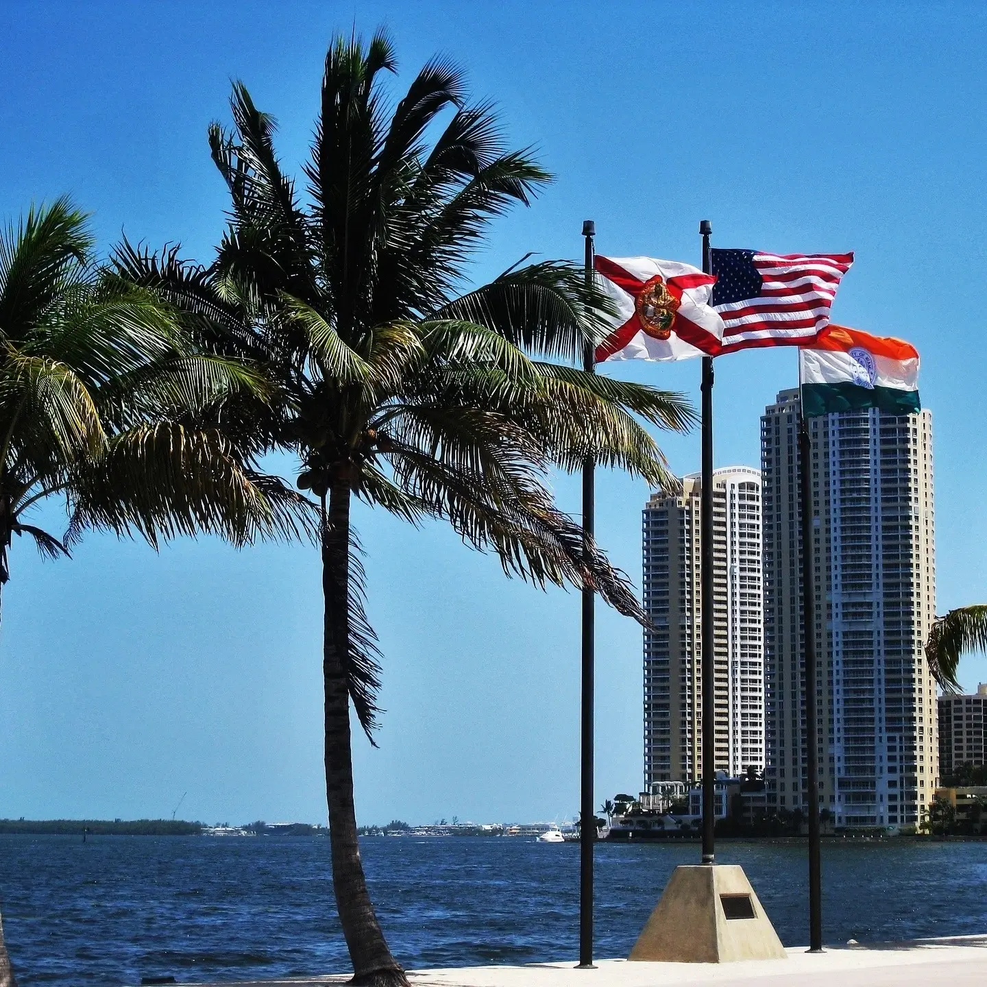 Two apartment Buildings and palm trees with american flags on a bright sunny day, blue skies in Turtle Run, Coral Springs, Fl