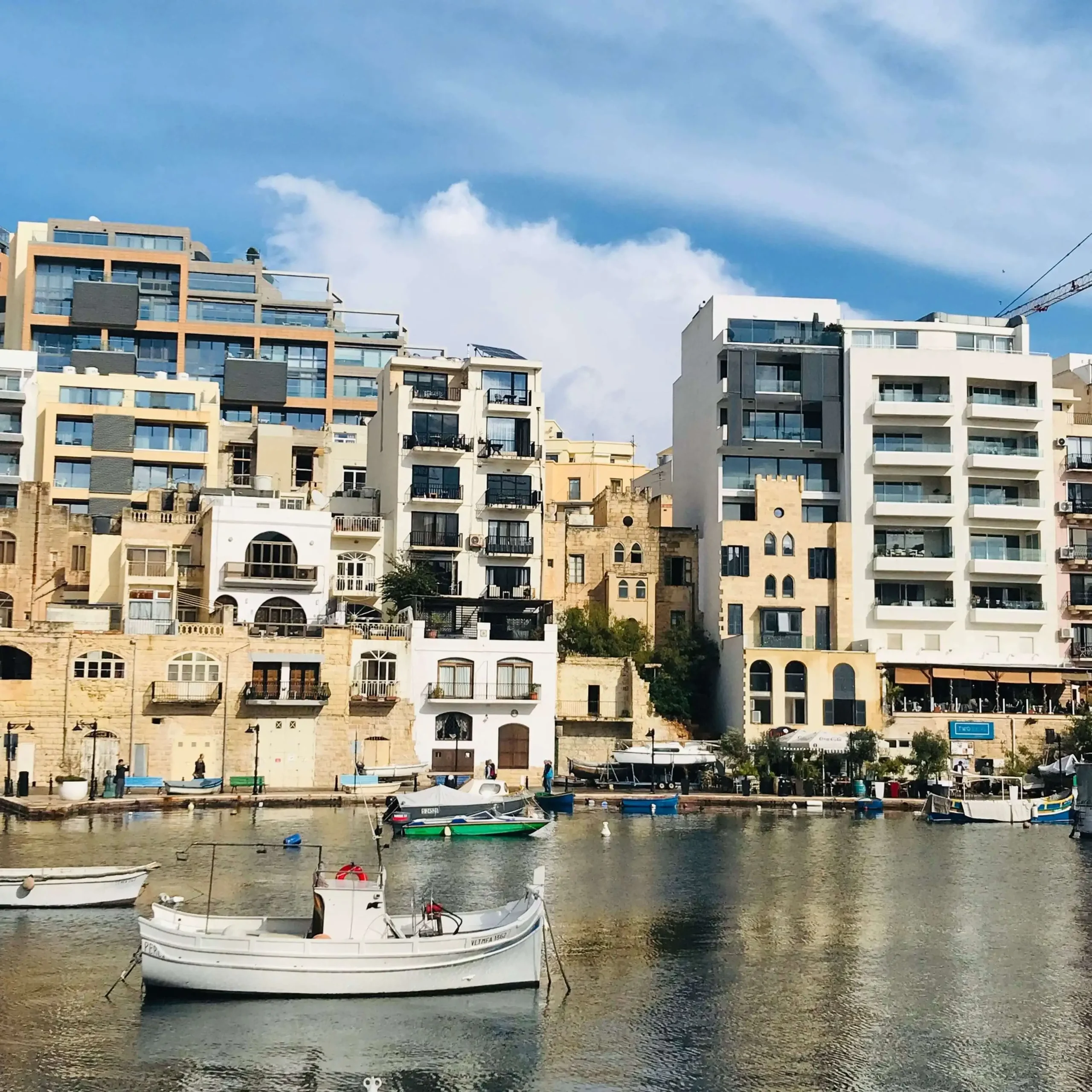 Waterfront apartment buildings in Welleby, Sunrise, FL, with fishing boats moored in the calm harbor, blue sky overhead.
