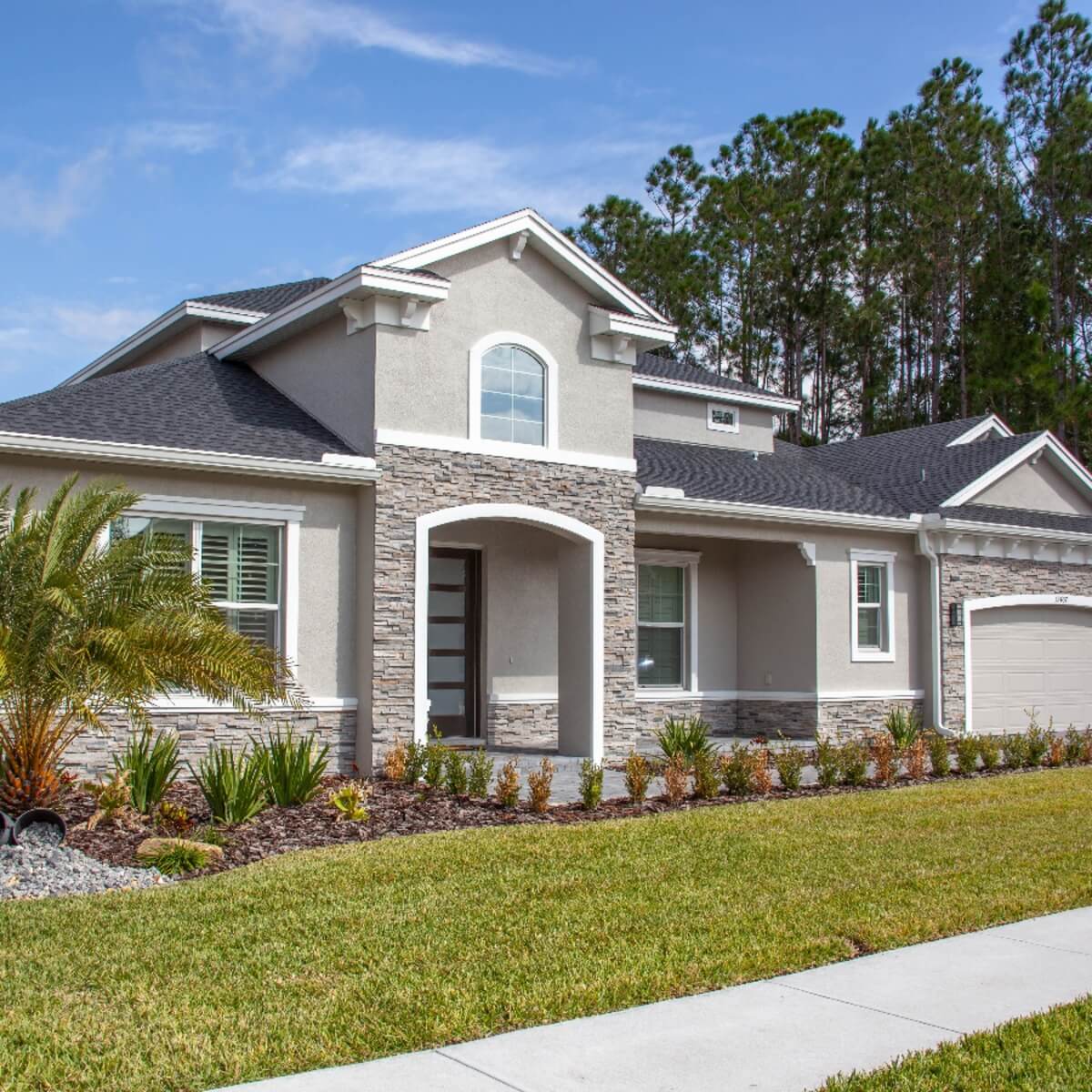Modern stucco single-family home with stone accents and palm trees in Del-Ida Park, Delray Beach