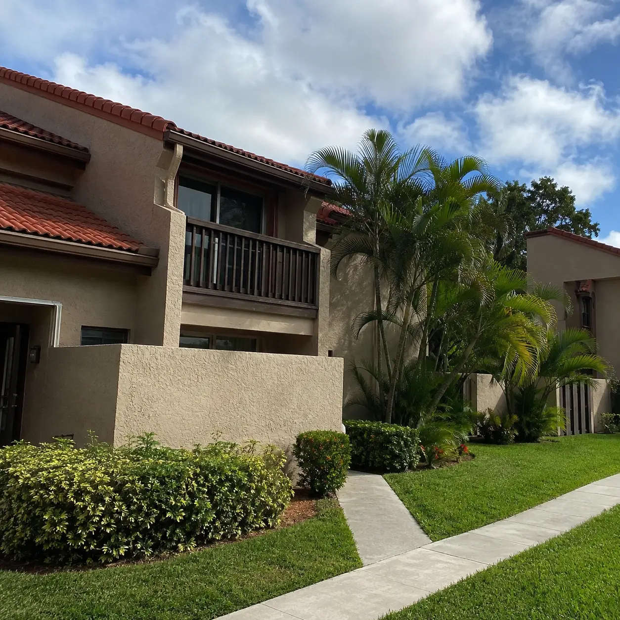 Two-story townhome with a tile roof, balcony, and palm trees in Malibu North / Island No. 2, Margate, FL.