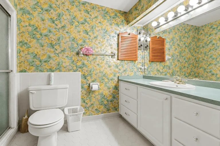Primary bathroom featuring green patterned walls and a large sink area